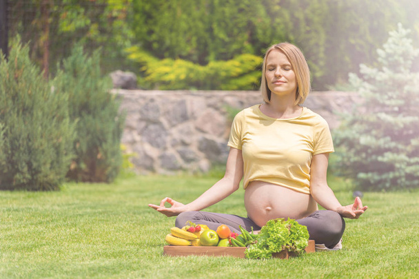 Pregnant woman practicing meditation and relaxation in nature - Foto, Bild