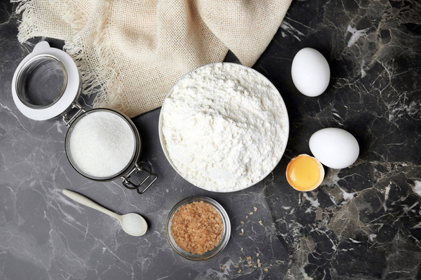 Bowl with flour, eggs and sugar on grey background, top view - Zdjęcie, obraz