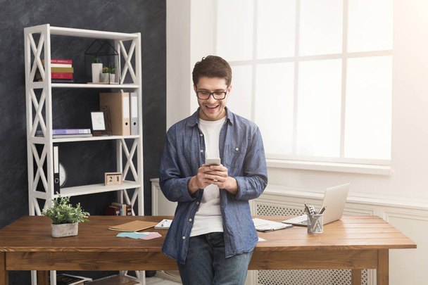 Розслаблений молодий бізнесмен використовує мобільний в офісі
 - Фото, зображення