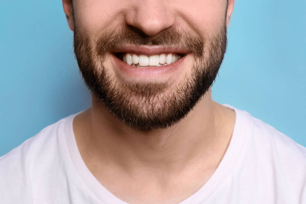 Young man with beautiful smile on grey background. Teeth whitening - Foto, afbeelding