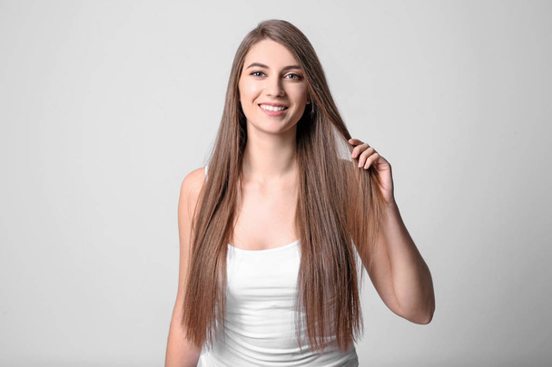 Portrait of young woman with long beautiful hair on light background - Fotoğraf, Görsel