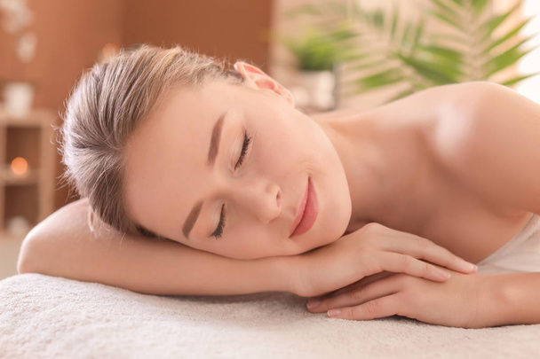 Young woman lying on massage table in spa salon - Foto, Imagem