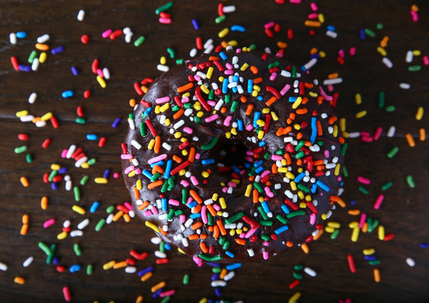 overhead studio shot of a donut with sprinkles on a wooden background unhealthy food concept  - 写真・画像