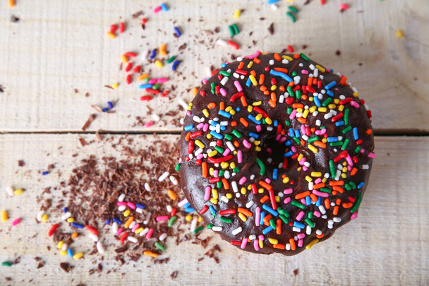 overhead studio shot of a donut with sprinkles on a wooden background unhealthy food concept  - Photo, image