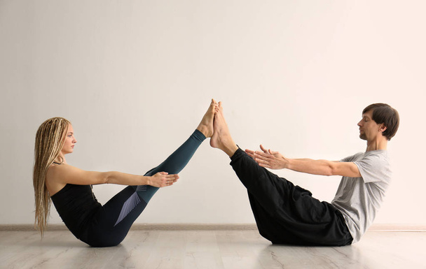 Young man and woman practicing yoga indoors - Фото, изображение