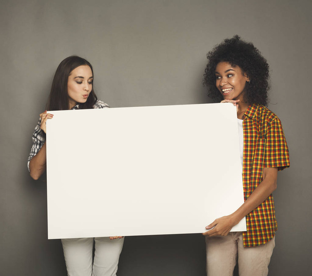 Two girlfriends holding blank white banner - Photo, Image