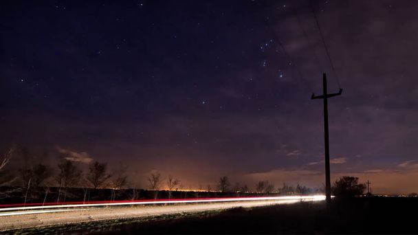 Cielo nocturno con estrellas. Carretera nocturna iluminada por coche
 - Foto, Imagen