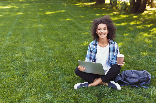 Счастливая молодая чернокожая женщина с ноутбуком в парке
 - Фото, изображение
