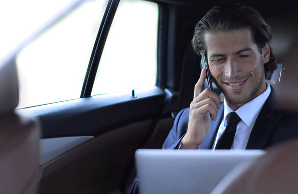 Handsome businessman using mobile phone in car. - Фото, изображение