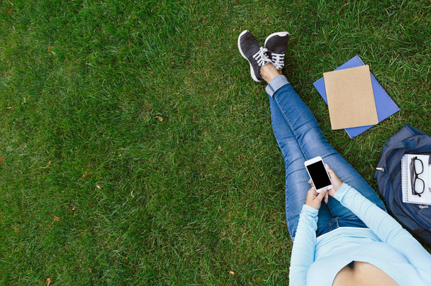 Meisje met mobiele telefoon zittend op het gras - Foto, afbeelding