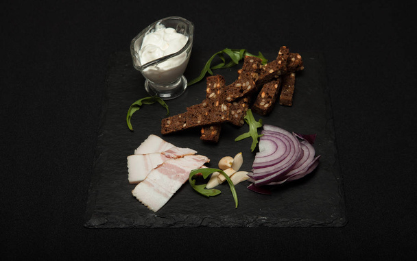 Ukrainian national food is lard salo with bread with purple onions on the black background - Foto, afbeelding