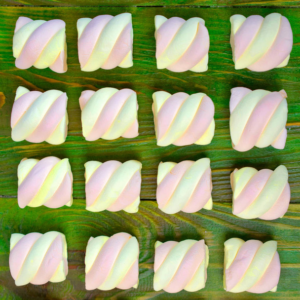 Pink marshmallow op een groene houten achtergrond. Plat lag of boven v - Foto, afbeelding