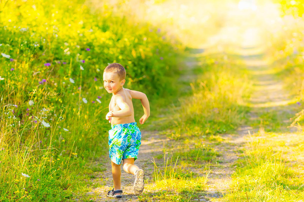 dorywczo obraz chłopca, który biegnie na polnej drodze i patrzy wstecz - Zdjęcie, obraz