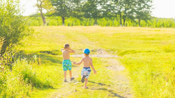 dos chicos en un camino de tierra en un hermoso día soleado. Un chico corrió y el otro cerró los oídos con las manos
 - Foto, imagen