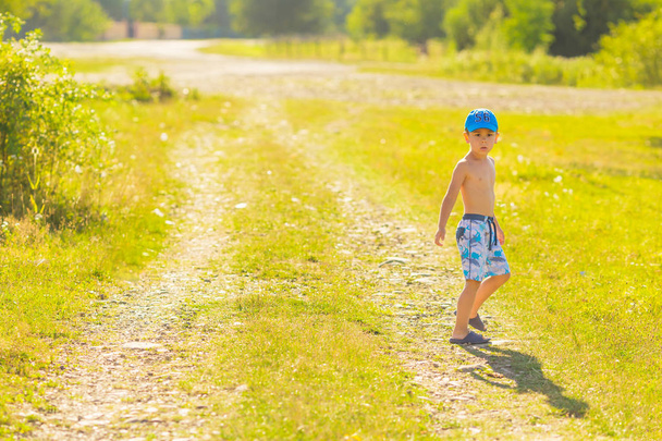 Boy in summer day standing on a dirt road passing the village - Valokuva, kuva