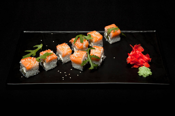 Sushi roll with salmon and avocado on plate on black background top view - Fotografie, Obrázek