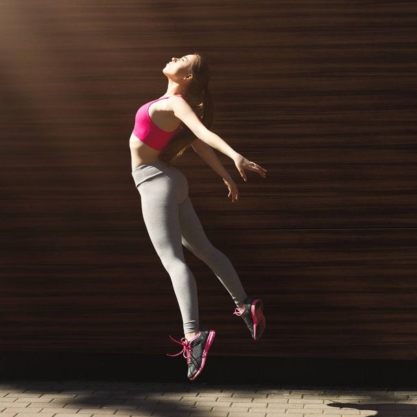 Güzel genç kadın kahverengi duvara atlama - Fotoğraf, Görsel