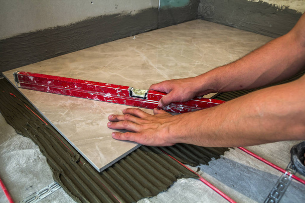 セラミック タイル、瓦職人のためのツール。労働者の手インストール床  - 写真・画像