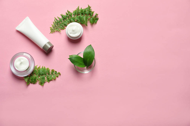 Different skin care cosmetic products with green leaves on color background, top view - Foto, immagini
