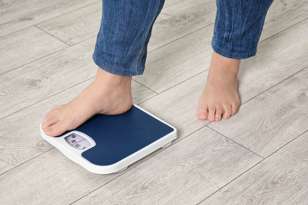 Overweight woman using scales indoors - Foto, Imagen