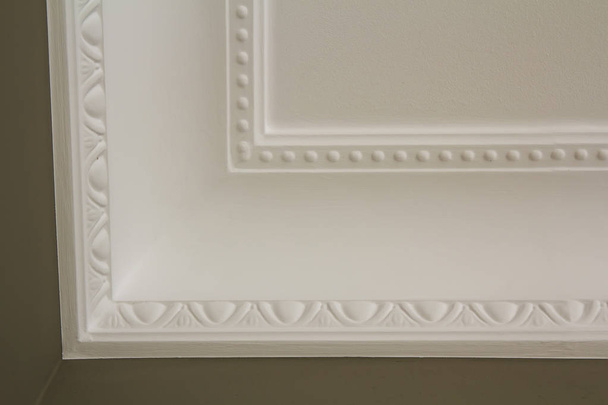 ornamentale weiße Formgebung Dekor an der Decke des weißen Raumes Nahaufnahme Detail. Innenrenovierung und Baukonzept. - Foto, Bild