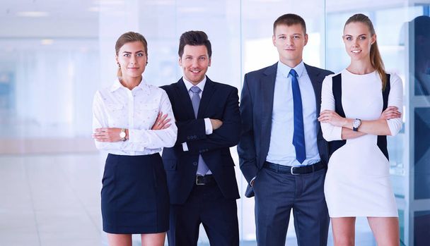 Усміхнена успішна бізнес команда, що стоїть в офісі
 - Фото, зображення