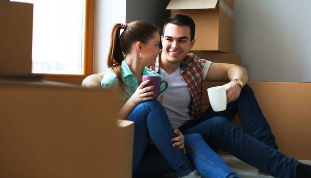 Portrait of young couple moving in new home sitting with cup - Fotoğraf, Görsel