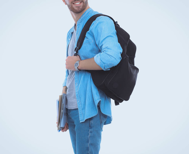 Young male student with school bag holding books isolated on white background - Valokuva, kuva