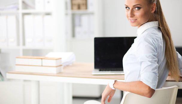 Attractive businesswoman sitting on a desk with laptop in the office - Photo, Image