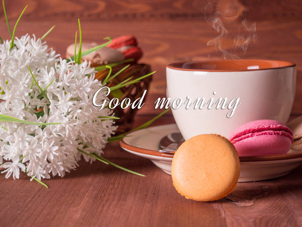 Colorful macarons with tea and flowers on wooden table. - Fotoğraf, Görsel
