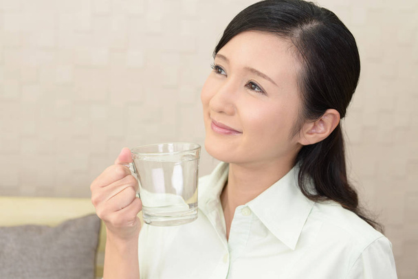 Vrouw die een glas water drinkt - Foto, afbeelding