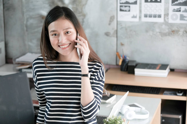 Mladá Asijská podnikatelka mluví chytrý telefon s úsměvem šťastná - Fotografie, Obrázek