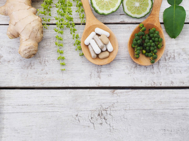 травяные таблетки в деревянной ложке и травах
 - Фото, изображение