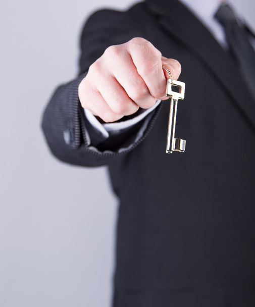 Real estate agent holds out a key - Photo, Image