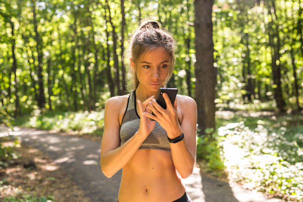sport, fitness, technologie en mensen concept - jonge vrouw atleet met hartslag horloge of fitness armband of tracker en smartphone meten van hartslag na een harde training - Foto, afbeelding