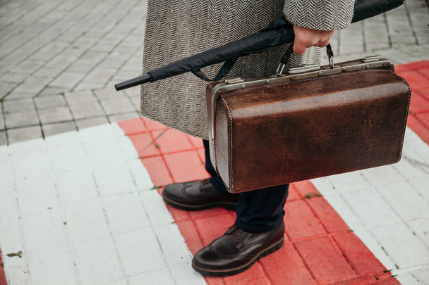 man with bag in coat is standing on pedestrian crossing - Zdjęcie, obraz