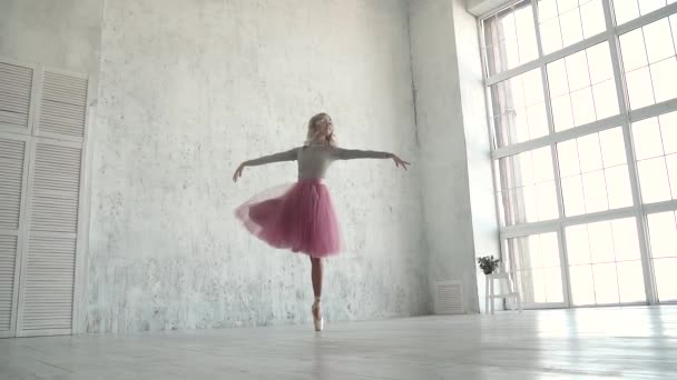 půvabná mladá baletka tančí v klasické tutu a pointes na pozadí velkého okna - Záběry, video