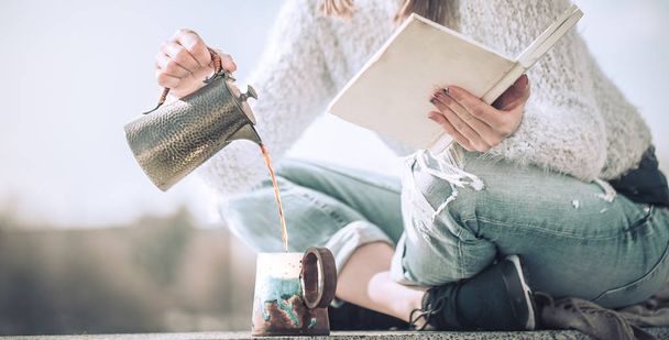 Mädchen trinkt Kaffee und liest Buch im Freien - Foto, Bild