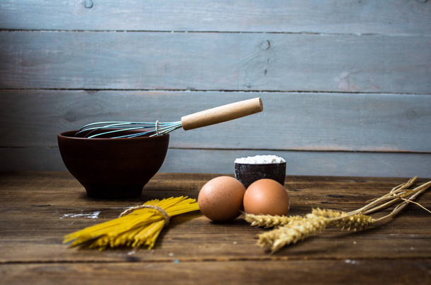 espaguetis y harina y huevos con utensilios de cocina sobre fondo de madera
 - Foto, Imagen