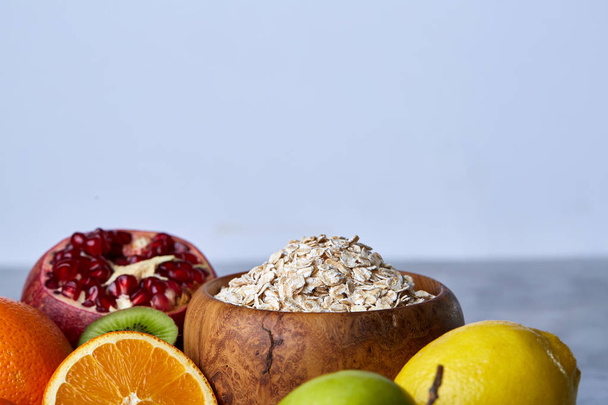 Bowl with oatmeal flakes served with fruits on wooden tray over rustic background, flat lay, selective focus - Photo, Image