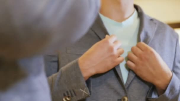 slow motion young guy dressed in new jacket poses in front of mirror in modern boutique for men - Materiał filmowy, wideo