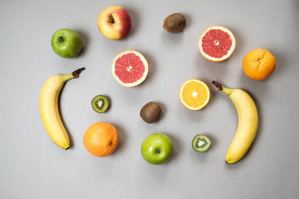 Colorful fresh fruit on Gray table. Orange, banana, apples, kiwi - Photo, Image