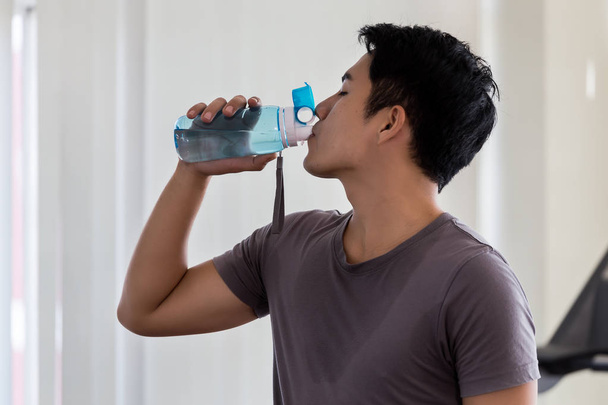 Boldog egészséges ember ivóvíz az edzőteremben. Miután a gyakorla - Fotó, kép