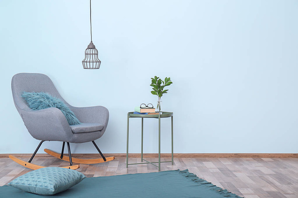 Interior elegante do quarto com cadeira de balanço confortável perto da parede clara
 - Foto, Imagem