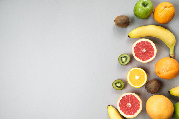 Colorful fresh fruit on Gray table. Orange, banana, apples, kiwi - Фото, изображение