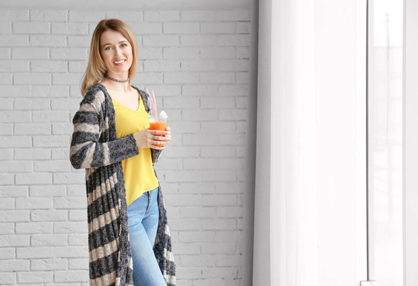 Young woman in striped cardigan near window indoors - Foto, Imagen