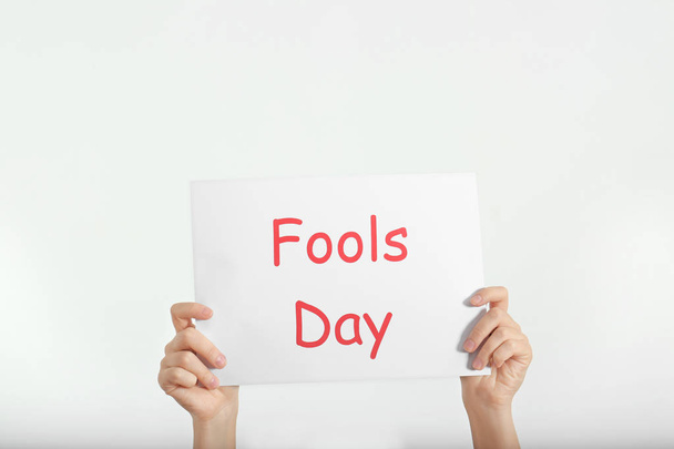 Woman holding sheet of paper with phrase "Fools day" on white background. 1st April celebration - Foto, immagini