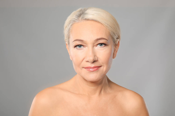 Portrait of beautiful mature woman on grey background. Skin care concept - Foto, Imagen