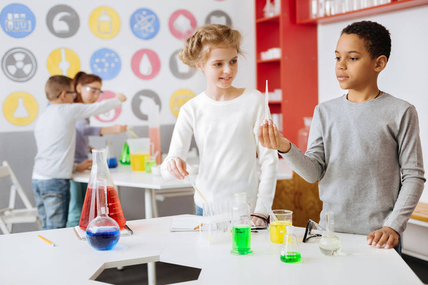 Upbeat schoolchildren looking at pipette with chemical - Foto, Bild