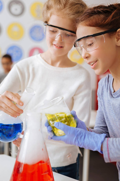 Cheerful girls mixing chemicals in a big flask - Foto, Bild